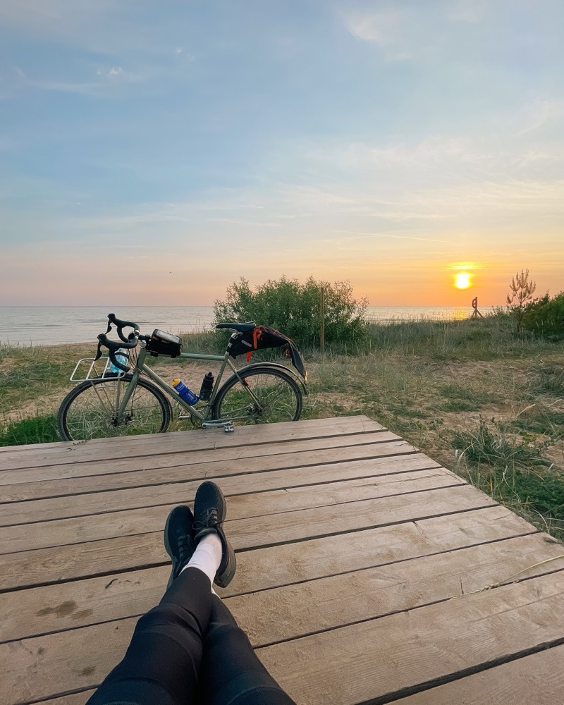A touring bike parked on a beach boardwalk at sunset